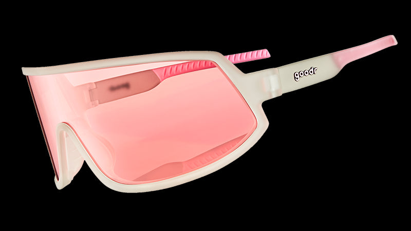 Three-quarter angle view of wraparound sunglasses with clear frames and a rose-tinted non-reflective single lens.