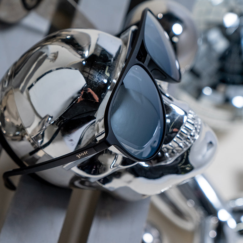 Side view of black and chrome aviator sunglasses displayed on a chrome skull.